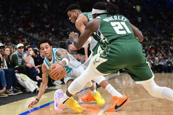 Charlotte Hornets guard Tre Mann (23) reaches for a loose ball against Milwaukee Bucks forward Giannis Antetokounmpo (34) and guard Patrick Beverley (21)
